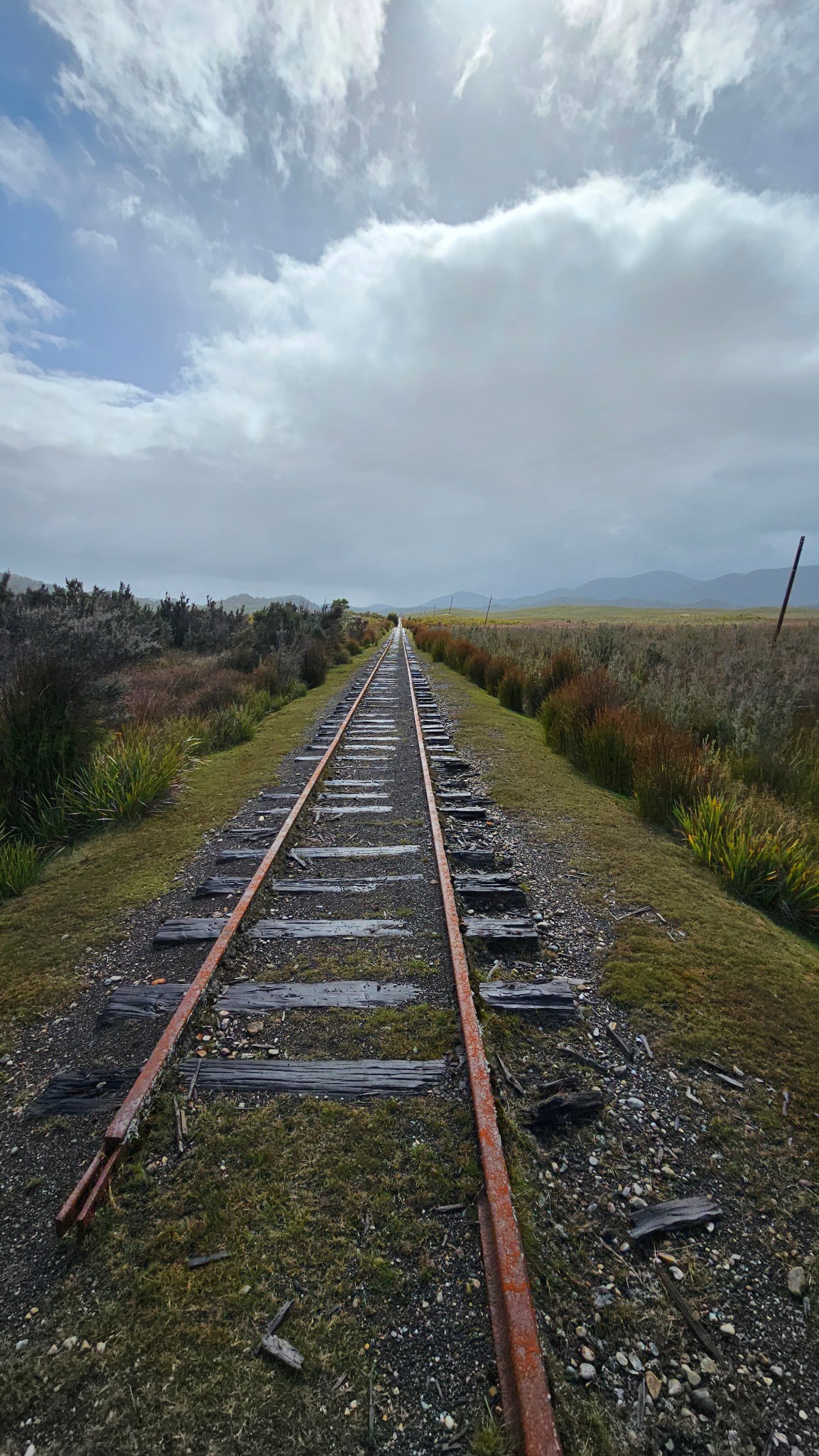 Old railway tracks stretching toward distant mountains
